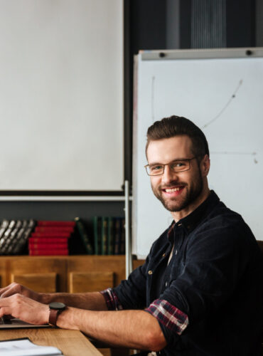 Image of handsome young man sitting near coffee while work with laptop. Coworking.